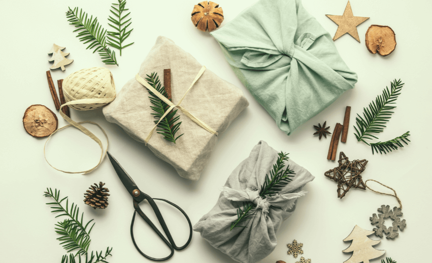 Eco-Friendly Decorations with fabric-wrapped gifts, natural twine, pine cones, cinnamon sticks, and wooden ornaments for sustainable holiday decor.