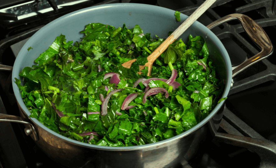 Sustainable Cooking Practices with sautéed leafy greens and red onions in a pot, using eco-friendly wooden utensils for a healthy, low-waste meal.